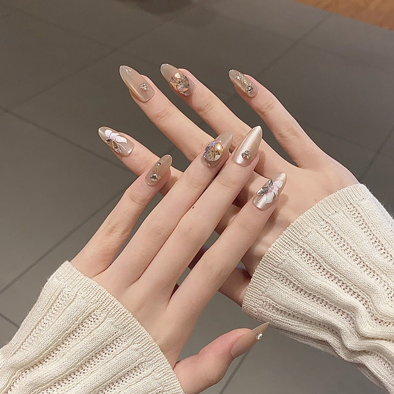 Glistening Elegance Long Almond Shaped Beige Nails with Charming Floral and Gemstone Accents