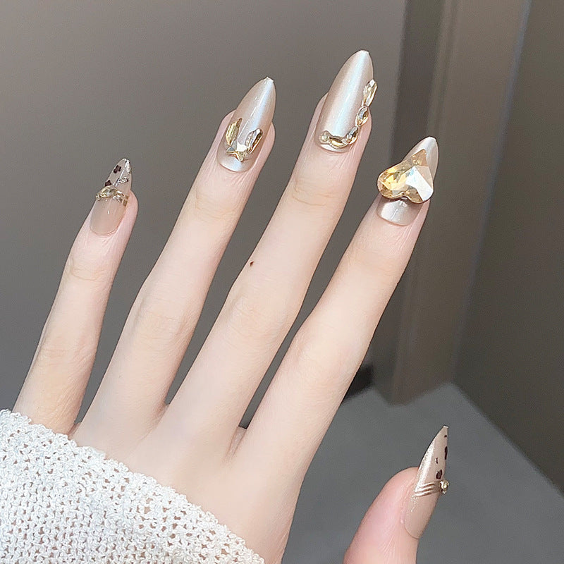 Glamorous Elegance Long Almond Beige Nails with Shimmery Accents and Eye-Catching Gem Details