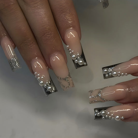 Sophisticated Long Coffin Beige Press-On Nails with Black Tips, Pearlescent Accents, and Chain Detail